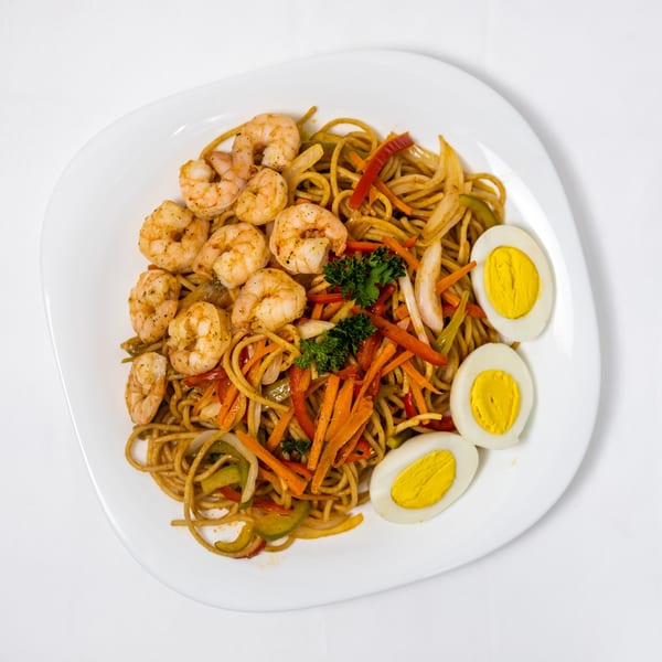 Shrimp chow mein with colorful vegetables, garnished with parsley and three hard-boiled egg halves.